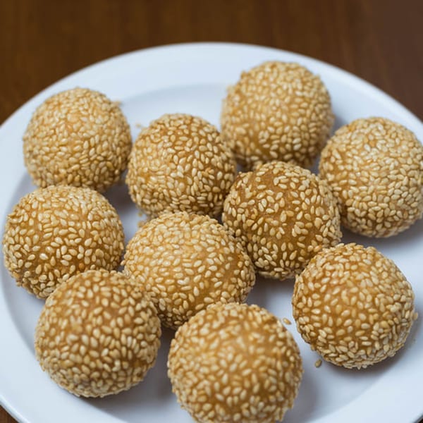 A white plate filled with golden-brown sesame balls, a popular Vietnamese dessert from Bon Mi.