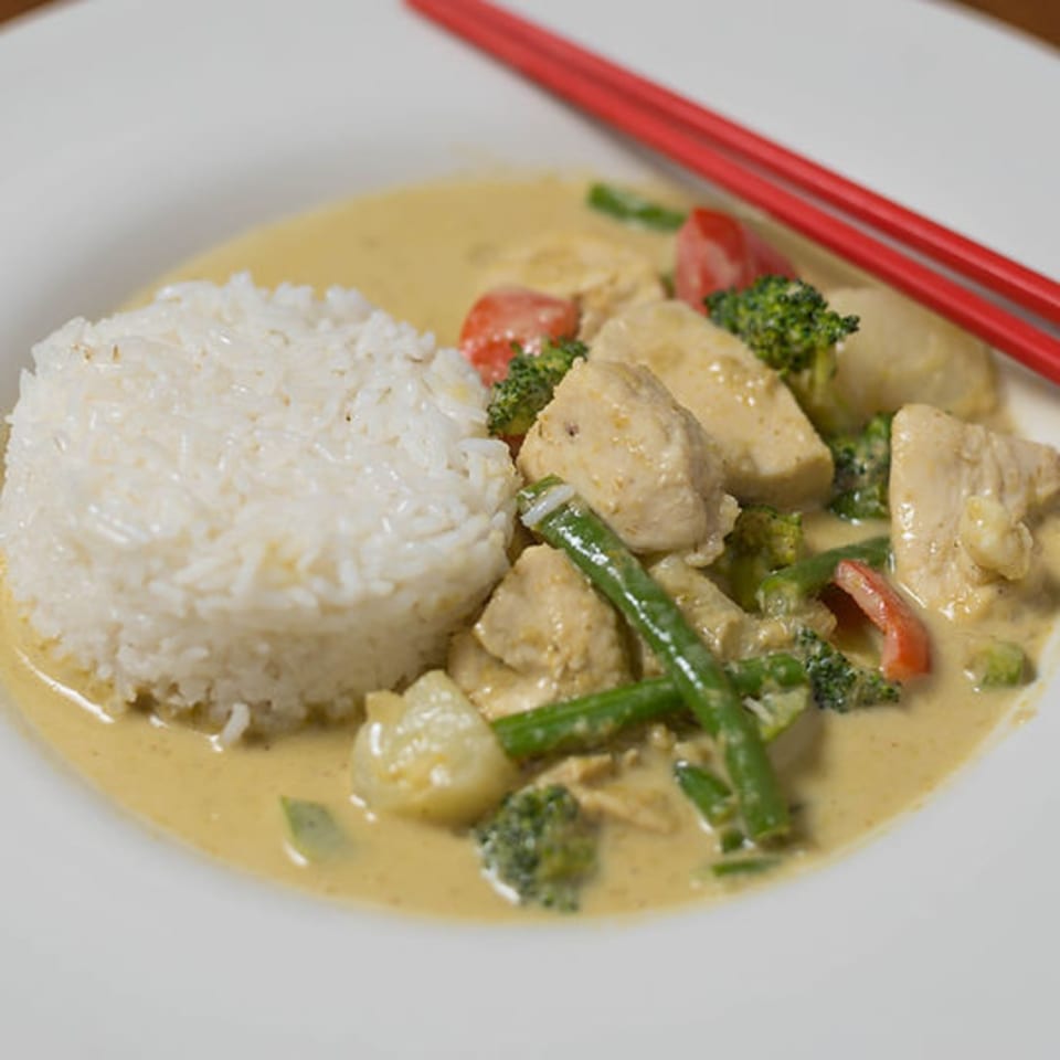 Bon Mi's yellow curry with chicken, broccoli, green beans, and rice, served with red chopsticks.